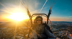 Mężczyzna latający motoparalotnią o zachodzie słońca